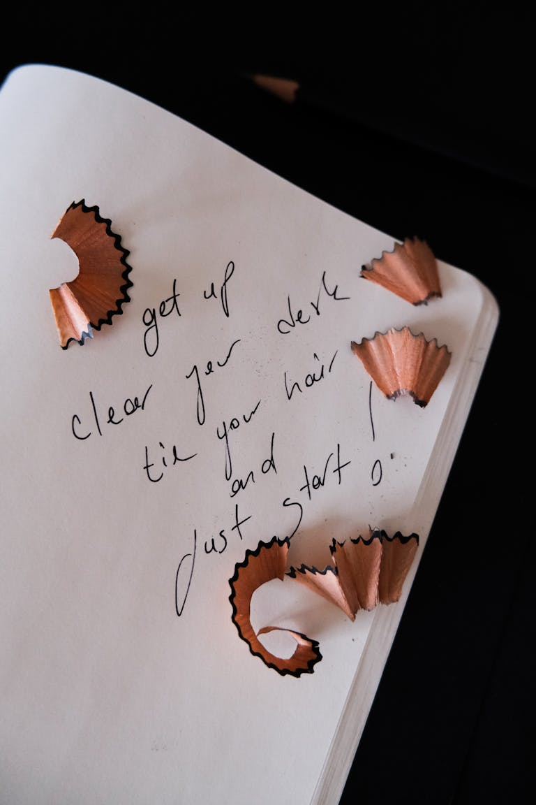Handwritten message with pencil shavings on open notebook, inspiring start and motivation.