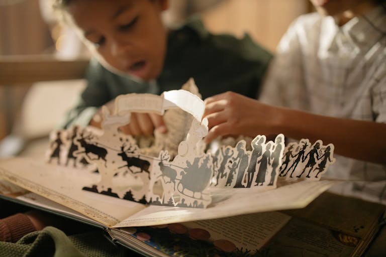 Two children engaged with a pop-up book, capturing the magic of reading indoors.