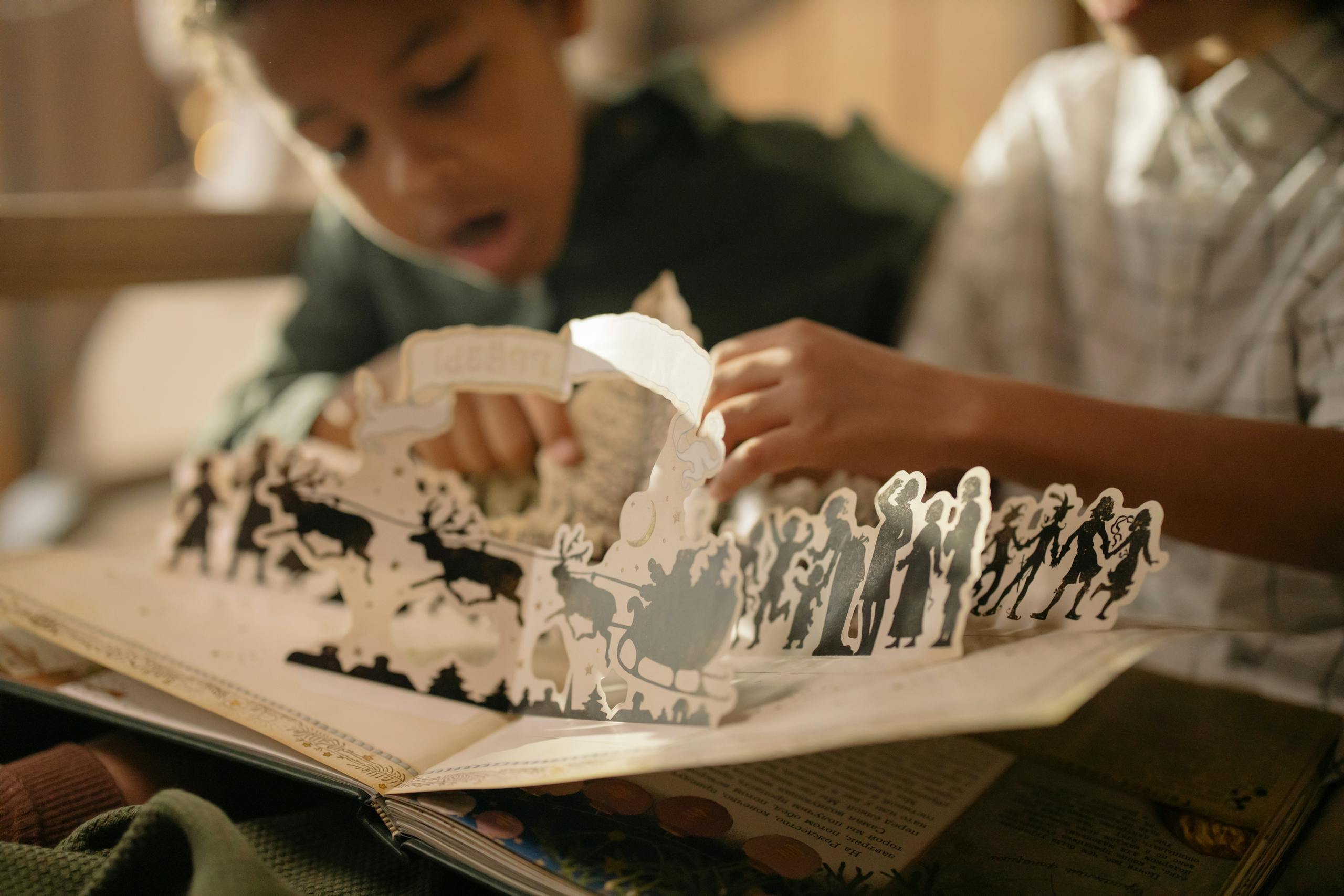 Two children engaged with a pop-up book, capturing the magic of reading indoors.